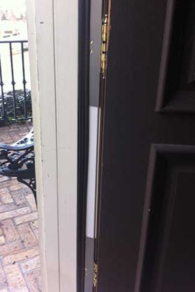 Aged bronze hinge shields installed to reinforce the hinge side of a door